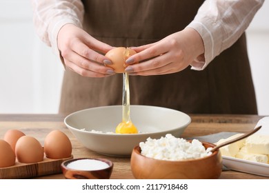 Woman adding egg into bowl with cottage cheese for preparing pancakes at kitchen table, closeup - Powered by Shutterstock