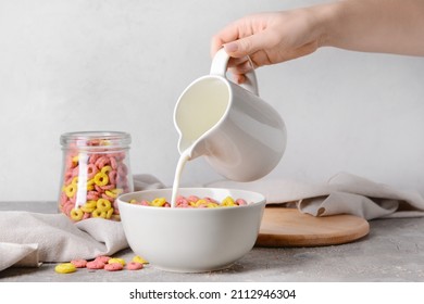 Woman adding milk to crunchy corn flakes rings in bowl - Powered by Shutterstock