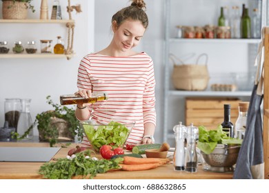 Woman Adding Olive Oil To Her Healthy Salad