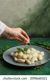 Woman Adding Parmesan Cheese Into Plate With Delicious Gnocchi At Table