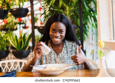 Woman Adding Salt To Food In Restaurant.