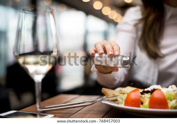 Woman adding salt to\
food in restaurant.