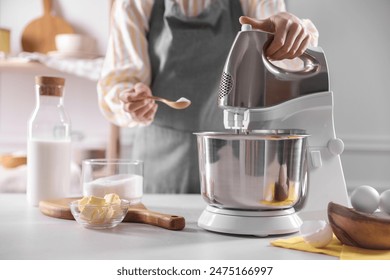 Woman adding sugar into bowl of stand mixer while making dough at table indoors, closeup - Powered by Shutterstock