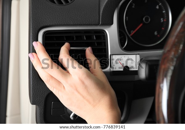 Woman adjusting\
air conditioner in car,\
closeup