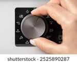 Woman adjusting modern white oven in kitchen.  Female hand pushing and turning knobs on oven control panel. Closeup