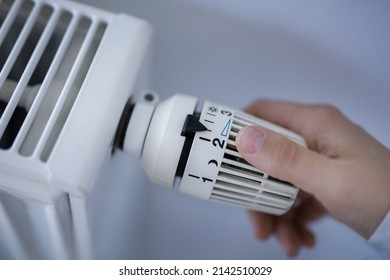 Woman Adjusting The Radiator Thermostat