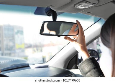 Woman Adjusting Rear View Mirror In Car