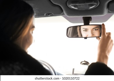 Woman Adjusting Rear View Mirror In Car