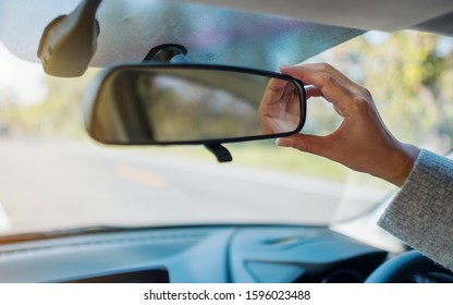 A woman adjusting a rear view mirror while driving car - Powered by Shutterstock - Get 15% off with code: PIKWIZARD15