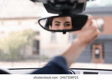 Woman adjusting rear view mirror inside her car, closeup - Powered by Shutterstock