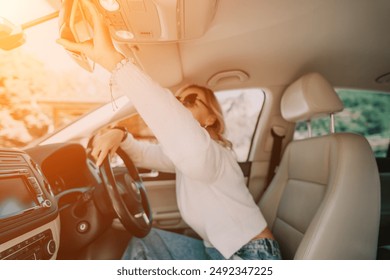 Woman Adjusting Rearview Mirror in a Car
