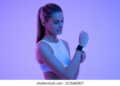 Woman adjusting settings of her fitness tracker or smartwatch before start of training session isolated on copy space background in neon light. Future sport. Keep fit - Shutterstock ID 2176682827