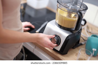 Woman adjusting speed of food processor. Pastry chef in kitchen turns on mixer or food processor concept - Powered by Shutterstock