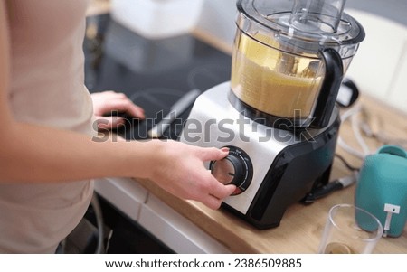 Woman adjusting speed of food processor. Pastry chef in kitchen turns on mixer or food processor concept