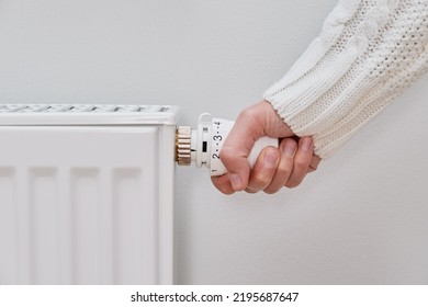 Woman adjusting temperature on heating radiator, Energy crisis concept in Europe, Rising costs in private households for gas bill due to inflation and war