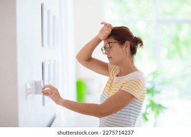 Woman adjusting thermostat. Central heating. Comfortable home temperature. Female setting room climate control regulator. Cooling on hot summer day. Indoor air conditioning. 