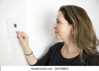 A Woman Adjusting Thermostat On Home Heating System - Shutterstock ID 396798853