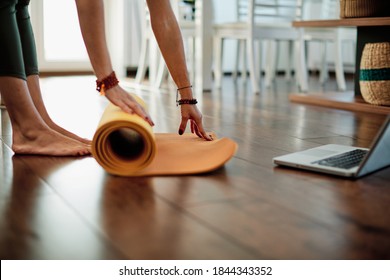 Woman adjusting yoga mat. There is a laptop on the floor. - Powered by Shutterstock