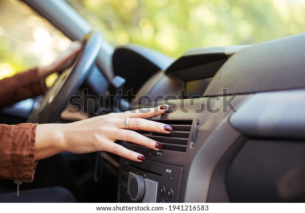 Woman adjusts the\
air conditioning in the\
car