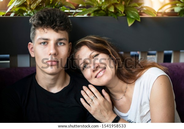 A woman\
admires her teenage son, who grew up so fast, hugs him and smiles.\
Mom and son relaxing and chatting together in a cafe. A woman feels\
respect and admiration for her\
son