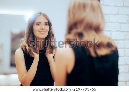 
Woman Admiring Her New Look in the Mirror at a Hair Salon. Happy client loving her new colored coiffure 
