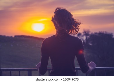 Woman admiring sunset from her balcony