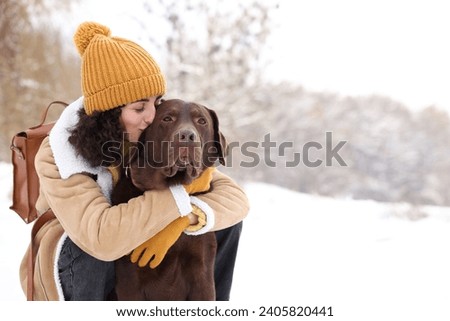 Woman with adorable Labrador Retriever dog in snowy park, space for text