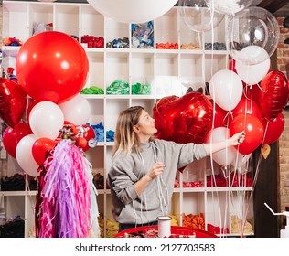 A Woman Aerodesigner With A Composition Of White, Red, Foil Balloons In The Form Of A Heart And Ball In The Store. Sale Of Balloons For Festive Decoration.