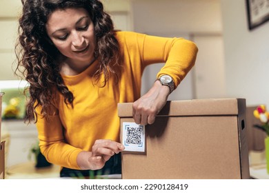 Woman affixing QR codes onto storage boxes. Concept organization, efficiency, or technology in storage management.