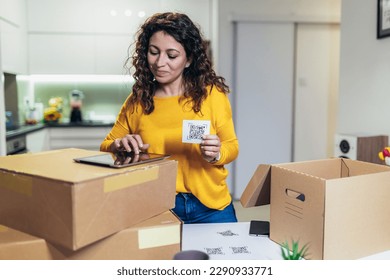 Woman affixing QR codes onto storage boxes. Concept organization, efficiency, or technology in storage management.