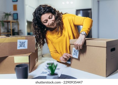 Woman affixing QR codes onto storage boxes. Concept organization, efficiency, or technology in storage management.
