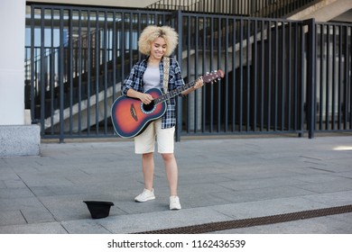 Woman African-American Appearance, Street Musician Earns Money By Playing The Guitar