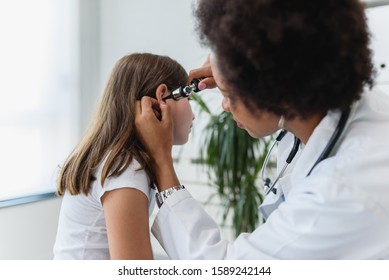 Woman Afro American Doctor General Practitioner Examining Ear Of A Ill Child. Ear Infections.