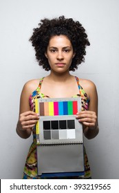 A Woman With Afro Hair Standing With A Color Chart In Front Of Her.