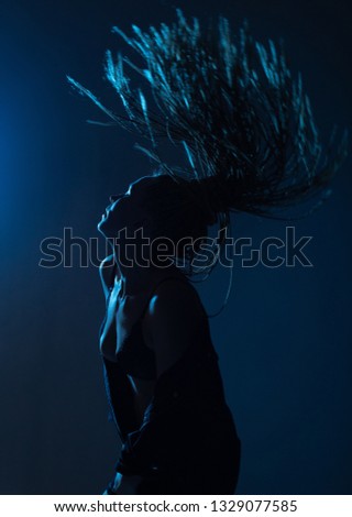 woman with afro pigtails in a raincoat on the dance floor with blue and red lights
