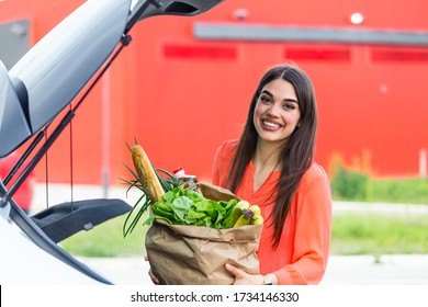 Woman after shopping in a mall or shopping center . Beautiful young woman shopping in a grocery store/supermarket, putting the groceries into her car in the pa