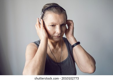 woman aged athlete listens to music through headphones during gymnastics
