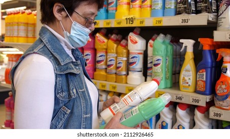 Woman In Aged Wearing Face Mask And Eye Glasses During Coronavirus Shopping And Stocking Up For Household Chemicals At Supermarket.