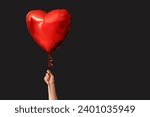 Woman with air balloon in shape of heart on black background. Valentine