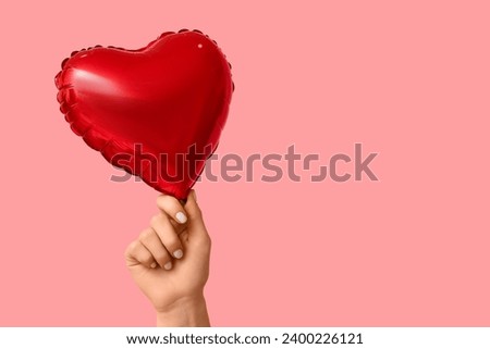 Woman with air balloon in shape of heart on pink background. Valentine's Day celebration