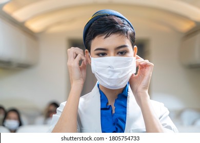 Woman Air Hostess Or Flight Attendant Boarding Plane Standing In Plane And Wearing Face Mask. Coronavirus Flu Virus Travel In Oversea Travel.