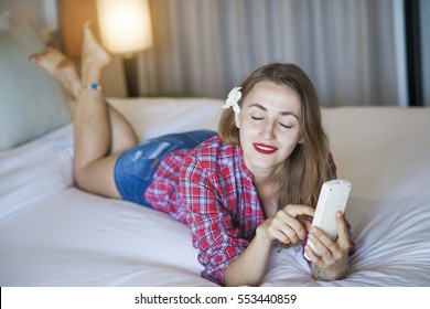 Woman With Aircon Remote Controller Lying On The Bed. 