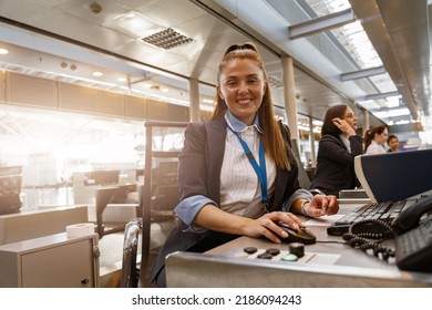 Woman airline employee working at airline check in counter in airport with colleagues on background