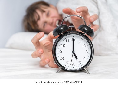 Woman with alarm clock is shocked a bell, does not want waking up at early