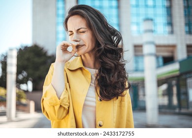 Woman with allergy symptom blowing nose. Outdoor shot of displeased Caucasian woman feels allergy, holds white tissuue, stands near tree with blossom, feels unwell, sneezes all time. Spring time. - Powered by Shutterstock