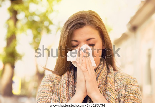 Woman with allergy\
symptoms blowing nose