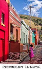 Woman in an alley with colorful houses in Bo Kaap district of Cape Town, South Africa