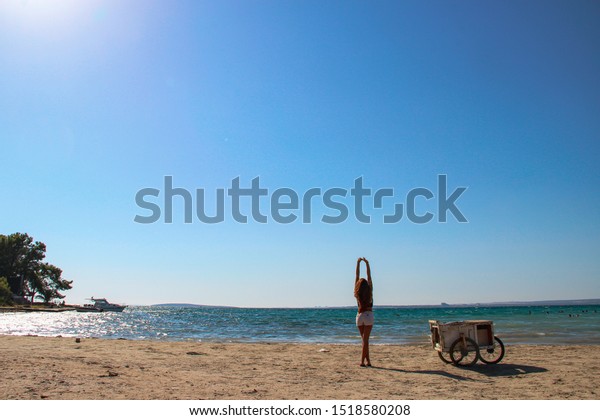 Woman alone\
with beach seller car at the beach looking over the horizon with \
wavy sea on a wind day in\
Mediterranean