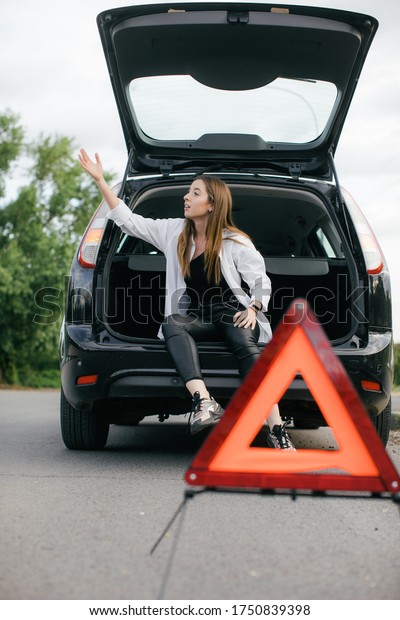 Woman alone driver checking a car\
engine for fix and repair problem with unhappy and dismal between\
waiting a car mechanic from car engine problem at\
roadside