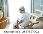 Woman alone in her living room in the afternoon, cuddling her pug and enjoying a relaxing moment of companionship with her dog, feeling the bond between them and the joy of spending time together